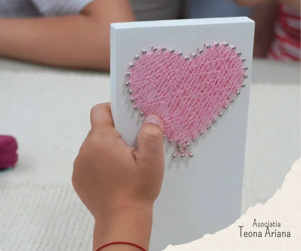 Copil care tine un tablou string art inima creat la atelier
