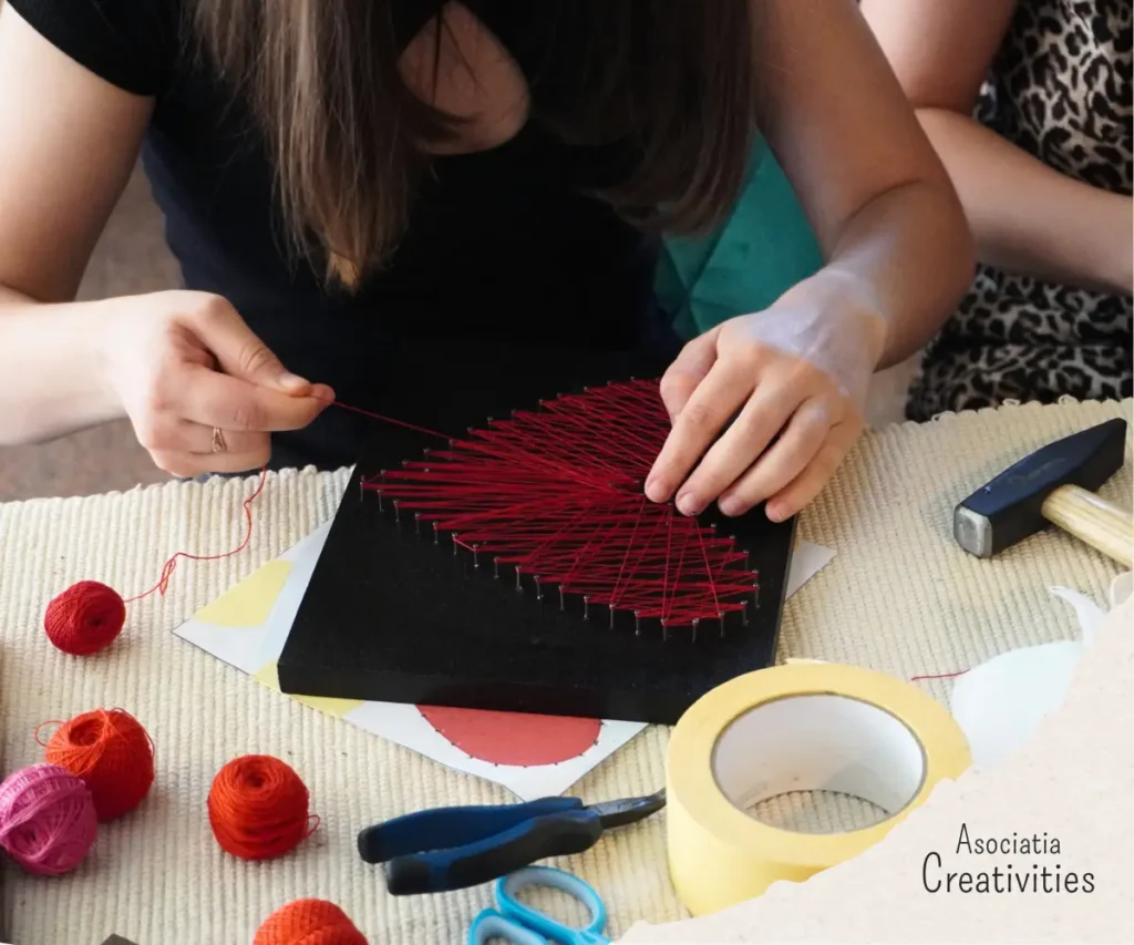 Crearea unui tablou string art cu inima rosie în timpul atelierului